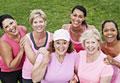 Group of six women of various ages in workout gear smiling in a group outdoors